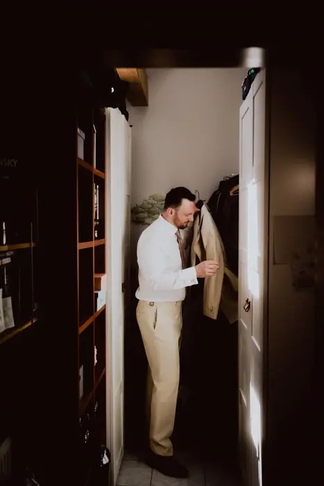 Hochzeitsfotograf Bayern Mann in kleinem Schrank zieht Jacke an Dokumentarische Editorial Hochzeitsfotografie
