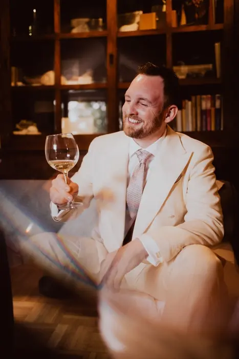 Hochzeitsfotograf Bayern Mann im eleganten Anzug mit Weinglas Dokumentarische Editorial Hochzeitsfotografie