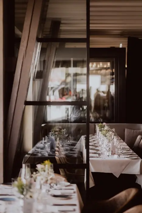 Hochzeitsfotograf Bayern Elegantes Restaurant mit eingedeckten Tischen und sanftem Licht Dokumentarische Editorial Hochzeitsfotografie