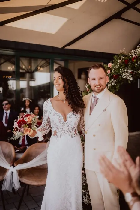 Hochzeitsfotograf Bayern Brautpaar bei ihrer Hochzeit mit Blumenstrauß, lächelnd und in festlicher Kleidung Dokumentarische Editorial Hochzeitsfotografie