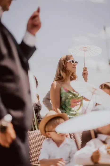 Hochzeitsfotograf Bayern Menschen in Sommerkleidung bei einem sonnigen Event mit Schirm Dokumentarische Editorial Hochzeitsfotografie