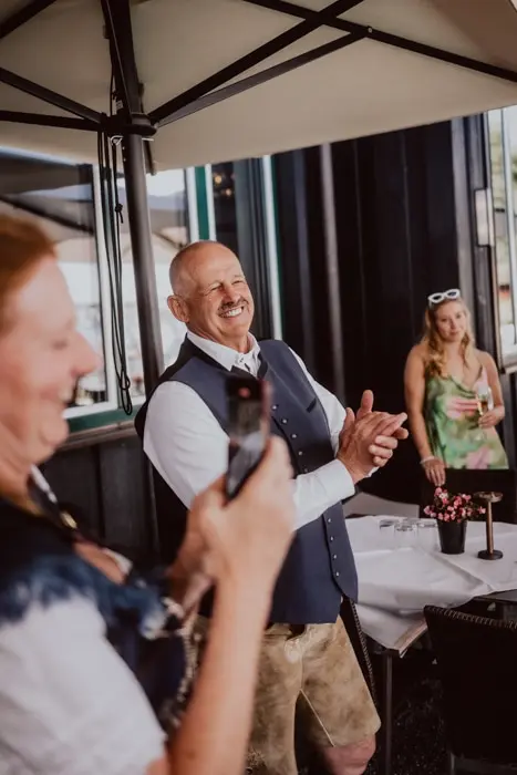 Hochzeitsfotograf Bayern Personen in traditioneller bayerischer Kleidung fröhlich bei einem Fest Dokumentarische Editorial Hochzeitsfotografie