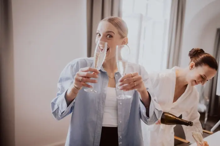 Hochzeitsfotograf Bayern Zwei Frauen genießen Champagner in einem feierlichen Ambiente Dokumentarische Editorial Hochzeitsfotografie