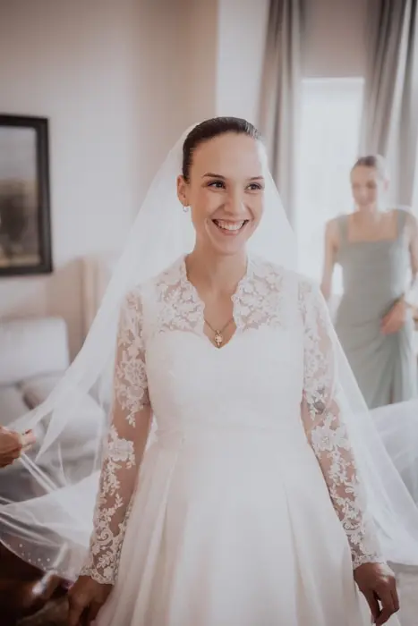 Hochzeitsfotograf Bayern Lachende Braut im Spitzenkleid mit Schleier am Hochzeitstag Dokumentarische Editorial Hochzeitsfotografie
