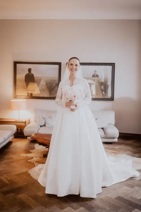 Hochzeitsfotograf Bayern Braut in eleganter weißer Hochzeitskleidung im stilvollen Wohnzimmer stehend Dokumentarische Editorial Hochzeitsfotografie