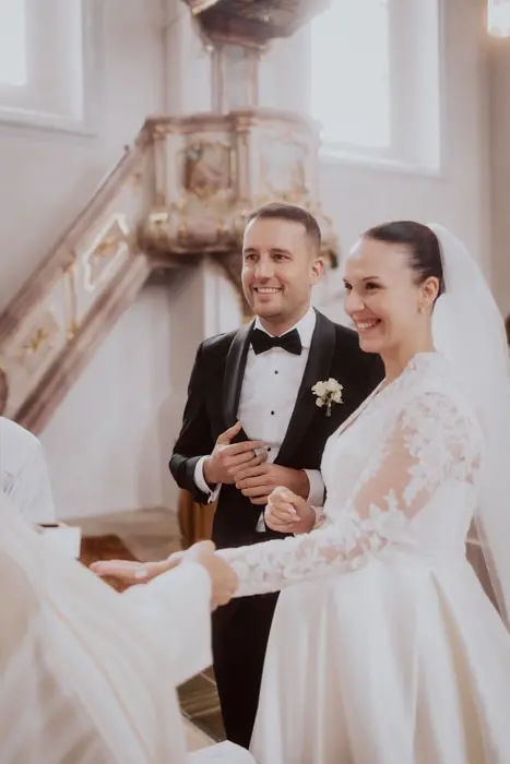 Hochzeitsfotograf Bayern Brautpaar lächelt in einer Kirche bei einer Hochzeitszeremonie Dokumentarische Editorial Hochzeitsfotografie