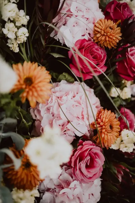 Hochzeitsfotograf Bayern Nahaufnahme von rosa Pfingstrosen, roten Rosen und orangefarbenen Chrysanthemen Dokumentarische Editorial Hochzeitsfotografie