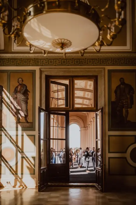 Hochzeitsfotograf Bayern Klassischer Flur mit offenen Türen zur Sonnenterrasse und Menschen im Hintergrund Dokumentarische Editorial Hochzeitsfotografie