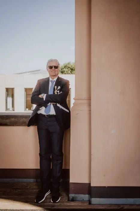 Hochzeitsfotograf Bayern Eleganter Mann in Anzug mit Sonnenbrille lehnt lässig an einer Wand Dokumentarische Editorial Hochzeitsfotografie