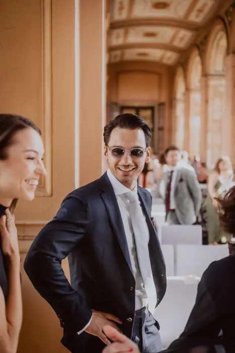 Hochzeitsfotograf Bayern Mann im Anzug lächelt in elegantem, lichtdurchflutetem Raum Dokumentarische Editorial Hochzeitsfotografie