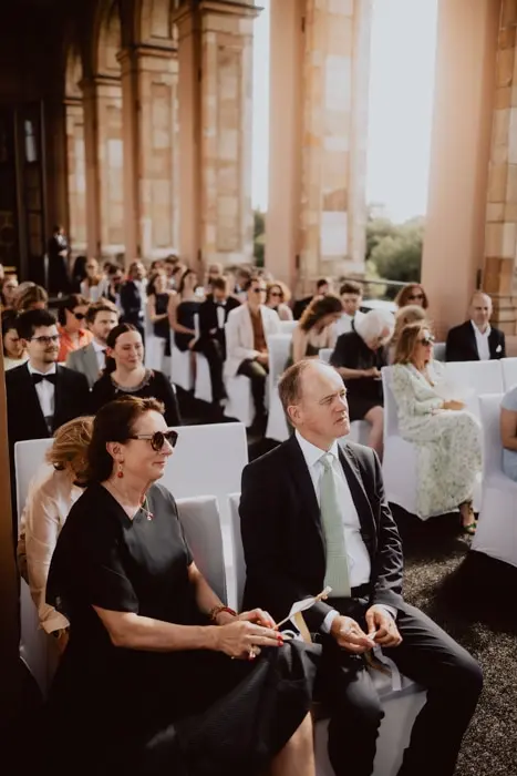 Hochzeitsfotograf Bayern Hochzeitsgäste auf einer Außenveranstaltung in formeller Kleidung Dokumentarische Editorial Hochzeitsfotografie