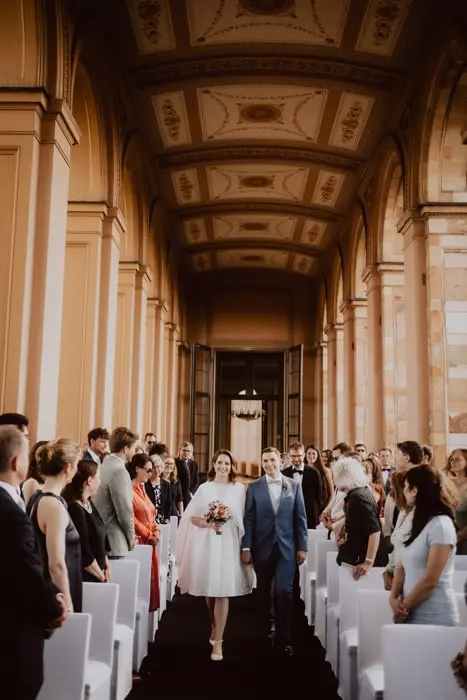 Hochzeitsfotograf Bayern Brautpaar geht durch Gäste bei Hochzeit in historischem Gebäude Dokumentarische Editorial Hochzeitsfotografie