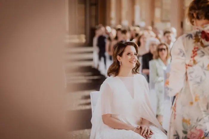 Hochzeitsfotograf Bayern Braut bei einer Hochzeitszeremonie mit Gästen im Hintergrund Dokumentarische Editorial Hochzeitsfotografie