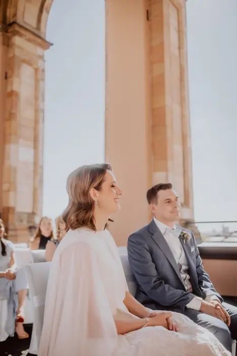 Hochzeitsfotograf Bayern Hochzeitspaar bei sonniger Trauung im Freien neben historischen Säulen Dokumentarische Editorial Hochzeitsfotografie