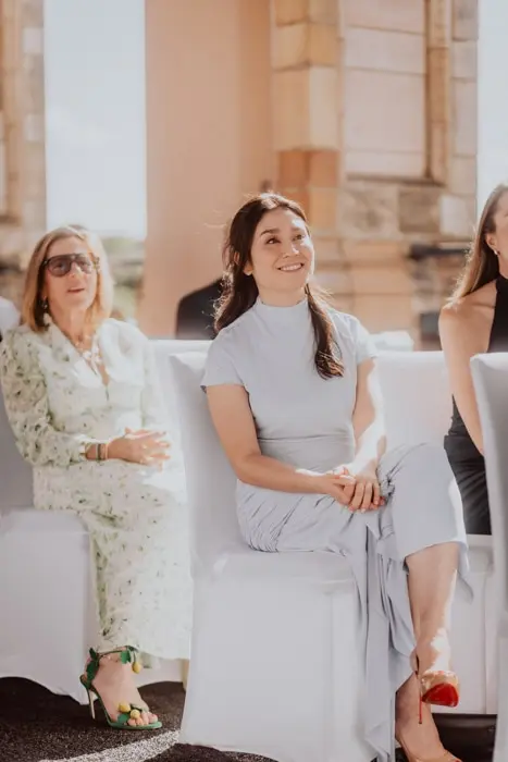 Hochzeitsfotograf Bayern Frauen sitzen bei einer eleganten Veranstaltung und lächeln Dokumentarische Editorial Hochzeitsfotografie