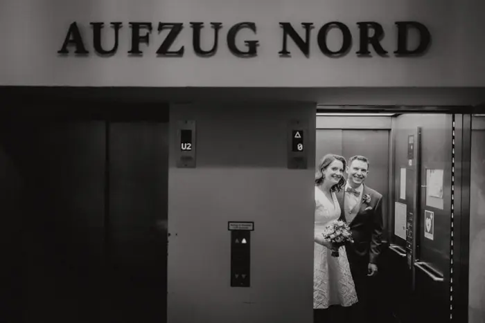 Hochzeitsfotograf Bayern Paar in einem Aufzug unter dem Schild AUFZUG NORD Dokumentarische Editorial Hochzeitsfotografie