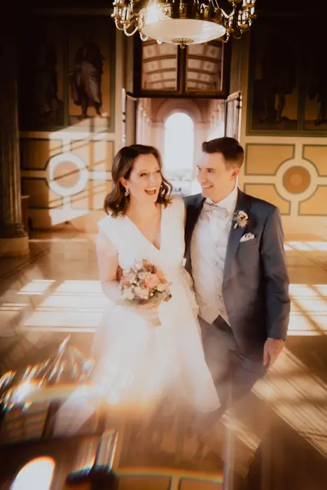 Hochzeitsfotograf Bayern Lächelndes Brautpaar in edlem Ballsaal bei Tageslicht Dokumentarische Editorial Hochzeitsfotografie