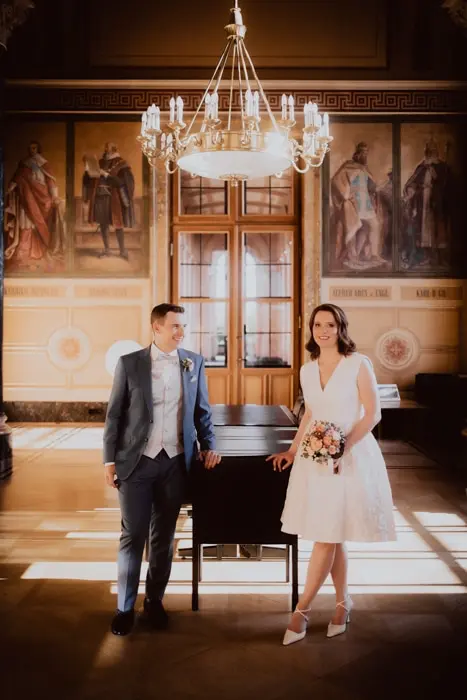 Hochzeitsfotograf Bayern Brautpaar vor historischem Gemälde und Kronleuchter im klassischen Saal Dokumentarische Editorial Hochzeitsfotografie