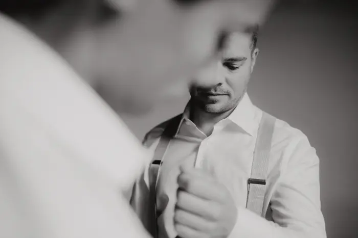 Hochzeitsfotograf Bayern Mann im weißen Hemd und Hosenträgern in Schwarz-Weiß-Fotografie Dokumentarische Editorial Hochzeitsfotografie
