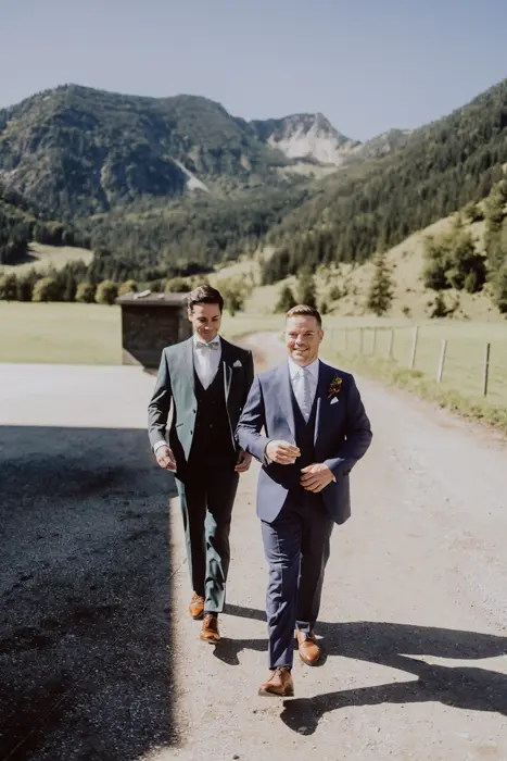 Hochzeitsfotograf Bayern Zwei Männer in Anzügen bei einer sommerlichen Hochzeit in den Bergen Dokumentarische Editorial Hochzeitsfotografie