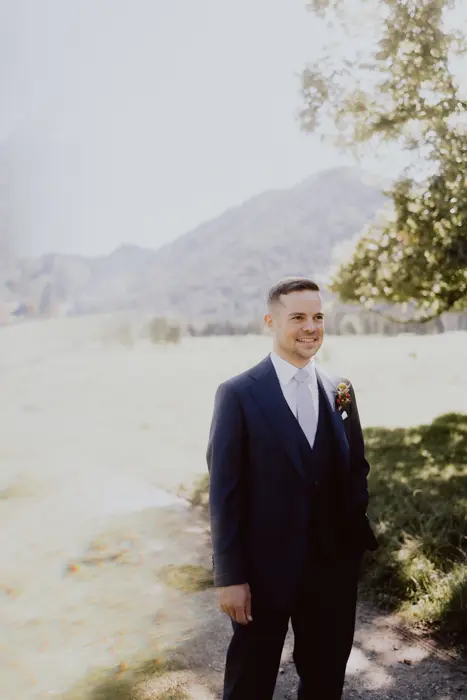 Hochzeitsfotograf Bayern Bräutigam in Anzug im Freien bei sonnigem Wetter Dokumentarische Editorial Hochzeitsfotografie