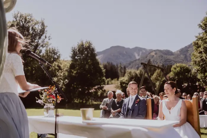 Hochzeitsfotograf Bayern Brautpaar bei Trauung im Freien mit Bergen im Hintergrund Dokumentarische Editorial Hochzeitsfotografie