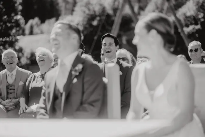 Hochzeitsfotograf Bayern Verschwommenes Schwarz-Weiß-Foto einer Hochzeitsgesellschaft, die herzlich lacht. Dokumentarische Editorial Hochzeitsfotografie