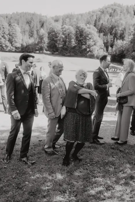 Hochzeitsfotograf Bayern Gruppe von Menschen bei einer Outdoor-Veranstaltung mit Bergen im Hintergrund Dokumentarische Editorial Hochzeitsfotografie