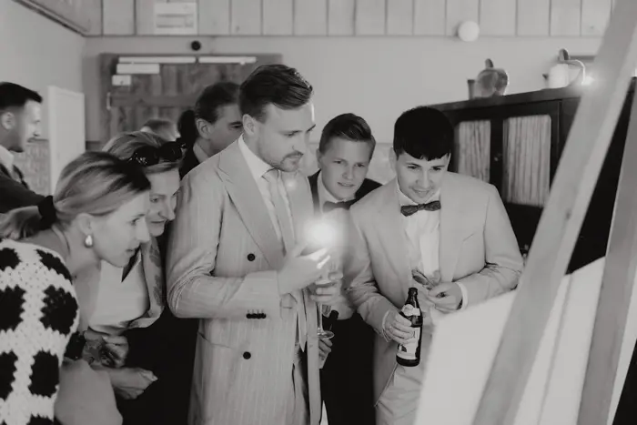 Hochzeitsfotograf Bayern Gruppe von Menschen betrachtet interessiert eine Wanderausstellung Dokumentarische Editorial Hochzeitsfotografie