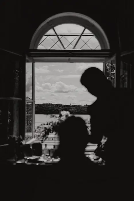 Hochzeitsfotograf Bayern Silhouetten vor einem Fenster mit Seeblick Dokumentarische Editorial Hochzeitsfotografie