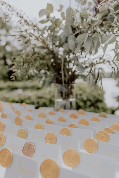 Hochzeitsfotograf Bayern Close-up von goldenen Platzkarten in festlicher Außenumgebung Dokumentarische Editorial Hochzeitsfotografie