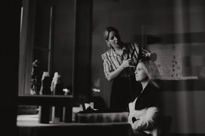 Hochzeitsfotograf Bayern Friseurin stylt Kundin in einem modernen Salon Dokumentarische Editorial Hochzeitsfotografie