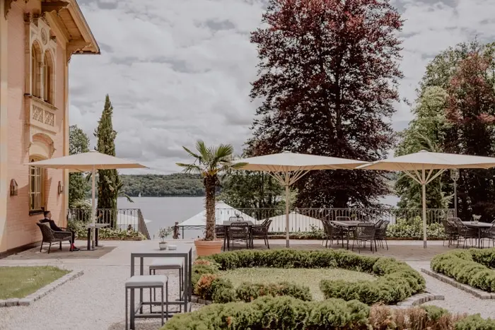 Hochzeitsfotograf Bayern Elegante Terrasse mit Sonnenschirmen und Seeblick Dokumentarische Editorial Hochzeitsfotografie