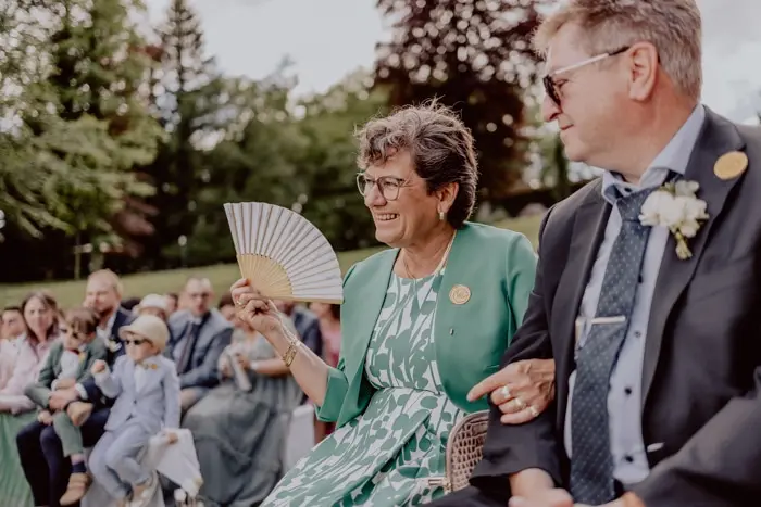 Hochzeitsfotograf Bayern Frau mit Fächer bei einer Outdoor-Hochzeit oder Veranstaltung Dokumentarische Editorial Hochzeitsfotografie