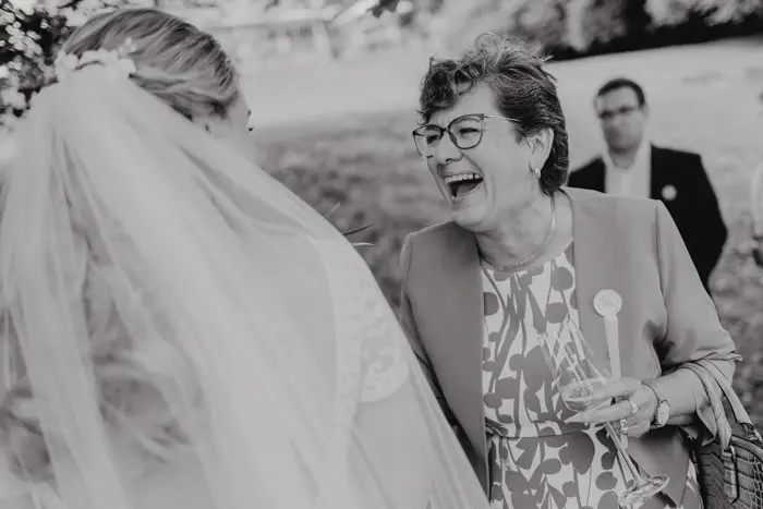 Hochzeitsfotograf Bayern Fröhliche Hochzeitsgäste unterhalten sich im Freien Dokumentarische Editorial Hochzeitsfotografie