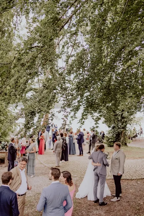 Hochzeitsfotograf Bayern Personen bei Hochzeit im Freien unter Bäumen Dokumentarische Editorial Hochzeitsfotografie