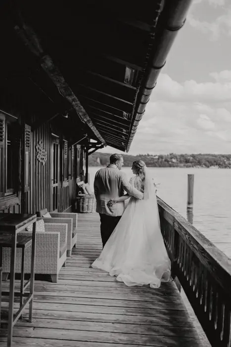 Hochzeitsfotograf Bayern Schwarz-Weiß-Foto eines Paares auf Holzterrasse am See Dokumentarische Editorial Hochzeitsfotografie