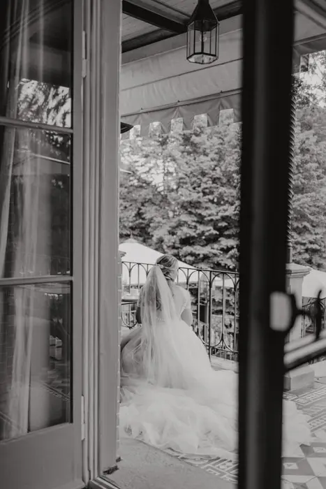 Hochzeitsfotograf Bayern Braut in Hochzeitskleid auf Veranda mit grüner Landschaft Dokumentarische Editorial Hochzeitsfotografie