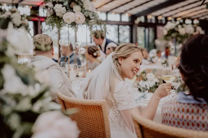 Hochzeitsfotograf Bayern Braut lächelnd bei Hochzeitsempfang im eleganten Saal Dokumentarische Editorial Hochzeitsfotografie