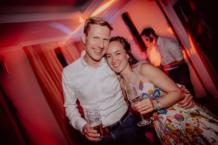 Hochzeitsfotograf Bayern Lächelndes Paar auf einer Party mit Getränken in der Hand Dokumentarische Editorial Hochzeitsfotografie