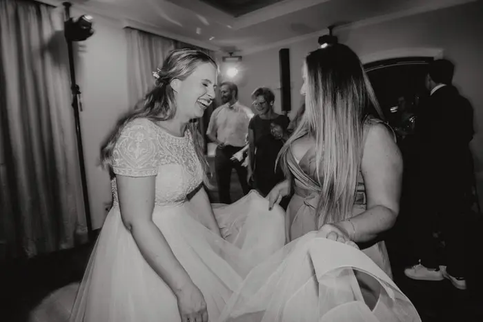 Hochzeitsfotograf Bayern Zwei Frauen lachen in eleganter Abendkleidung bei einer Hochzeit Dokumentarische Editorial Hochzeitsfotografie