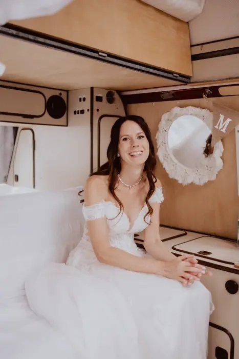 Hochzeitsfotograf Bayern Braut in einem festlich geschmückten Vintage-Wohnmobil Dokumentarische Editorial Hochzeitsfotografie