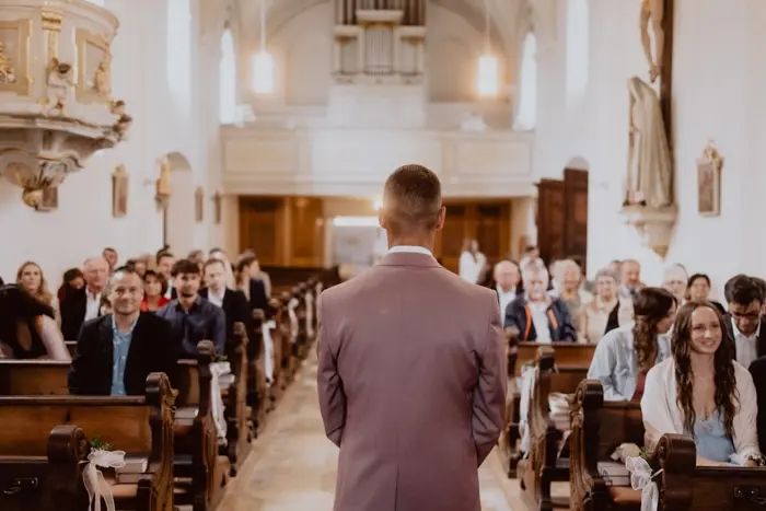 Hochzeitsfotograf Bayern Hochzeitszeremonie in Kirche mit Bräutigam und Gästen Dokumentarische Editorial Hochzeitsfotografie