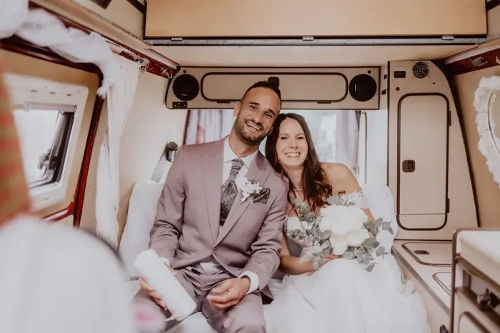 Hochzeitsfotograf Bayern Brautpaar in einem individuell gestalteten Hochzeitsauto Dokumentarische Editorial Hochzeitsfotografie