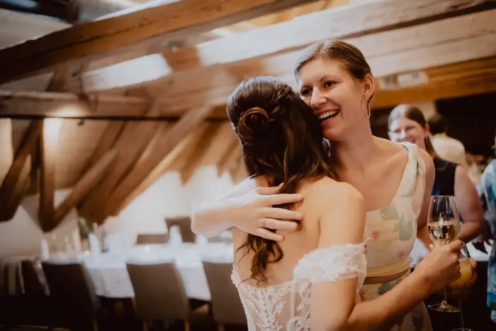 Hochzeitsfotograf Bayern Zwei Freundinnen bei einer Hochzeit in herzlicher Umarmung Dokumentarische Editorial Hochzeitsfotografie
