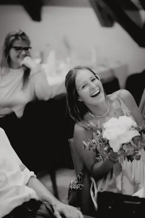 Hochzeitsfotograf Bayern Lachende Frau hält Blumenstrauß in schwarz-weißem Bild Dokumentarische Editorial Hochzeitsfotografie