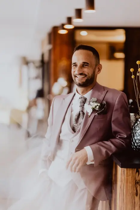 Hochzeitsfotograf Bayern Lächelnder Bräutigam in schickem Anzug an Hochzeitstag Dokumentarische Editorial Hochzeitsfotografie