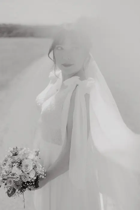 Schwarz Weiß Foto einer Braut im Brautkleid und Brautstrauss in der Hand