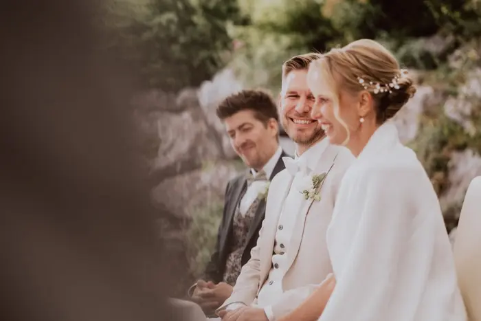 Hochzeitsfotograf Bayern Hochzeitsgesellschaft mit Braut und Bräutigam in formeller Kleidung im Freien Dokumentarische Editorial Hochzeitsfotografie