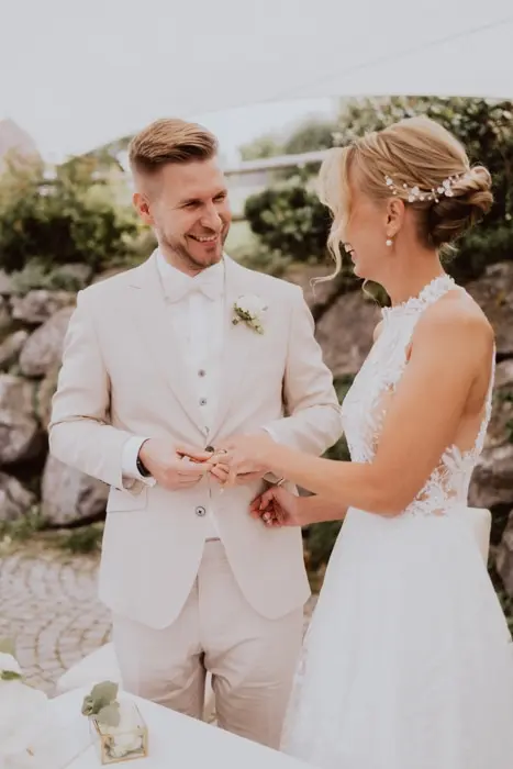 Hochzeitsfotograf Bayern Brautpaar tauscht Ringe während Hochzeitszeremonie im Freien Dokumentarische Editorial Hochzeitsfotografie